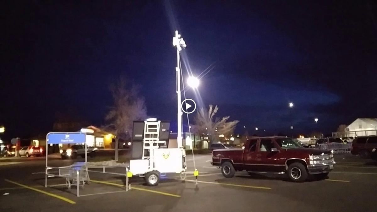 Surveillance trailer with a lit mast in a parking lot at night