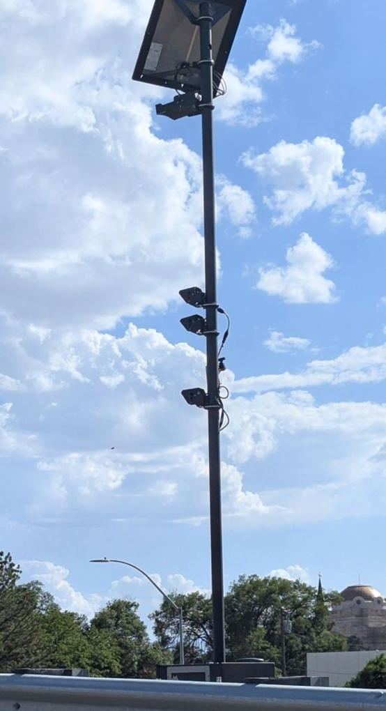 Tall solar camera pole beside a highway guardrail